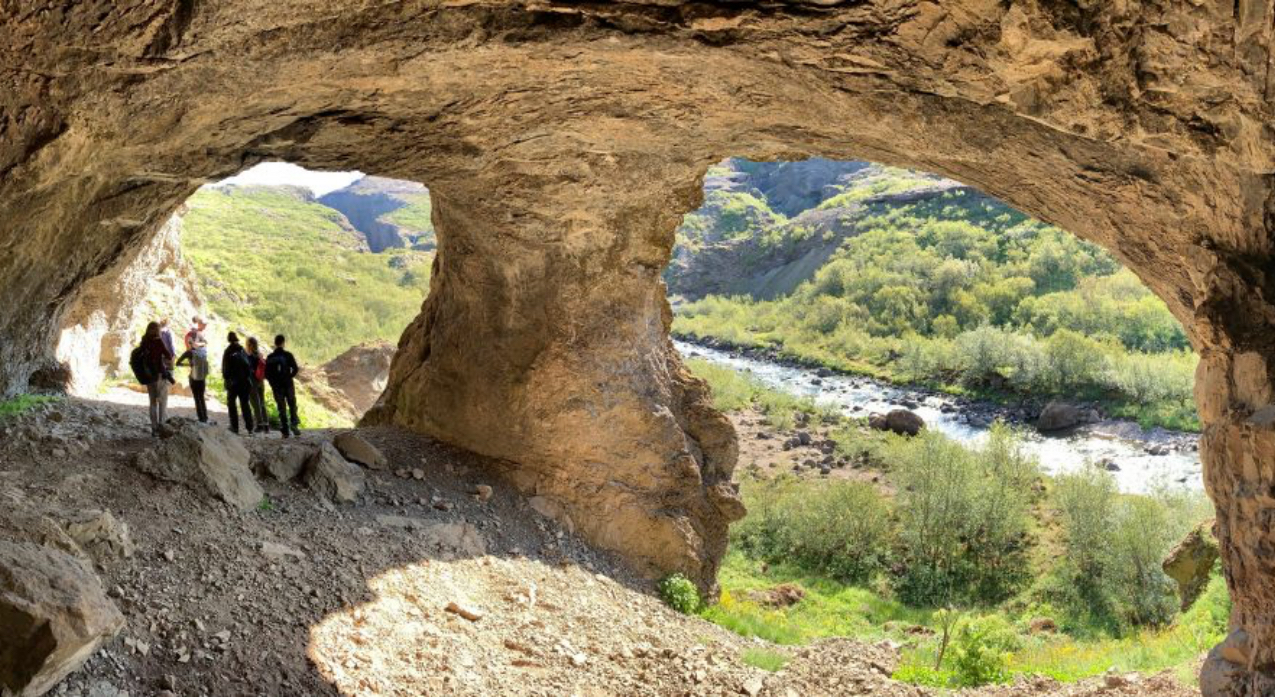 Group of students under rock formation on bank of river