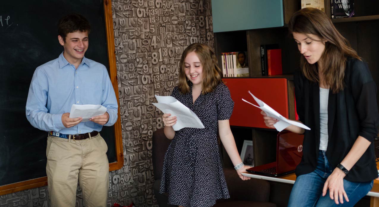 group of three students smiling and making a presentation