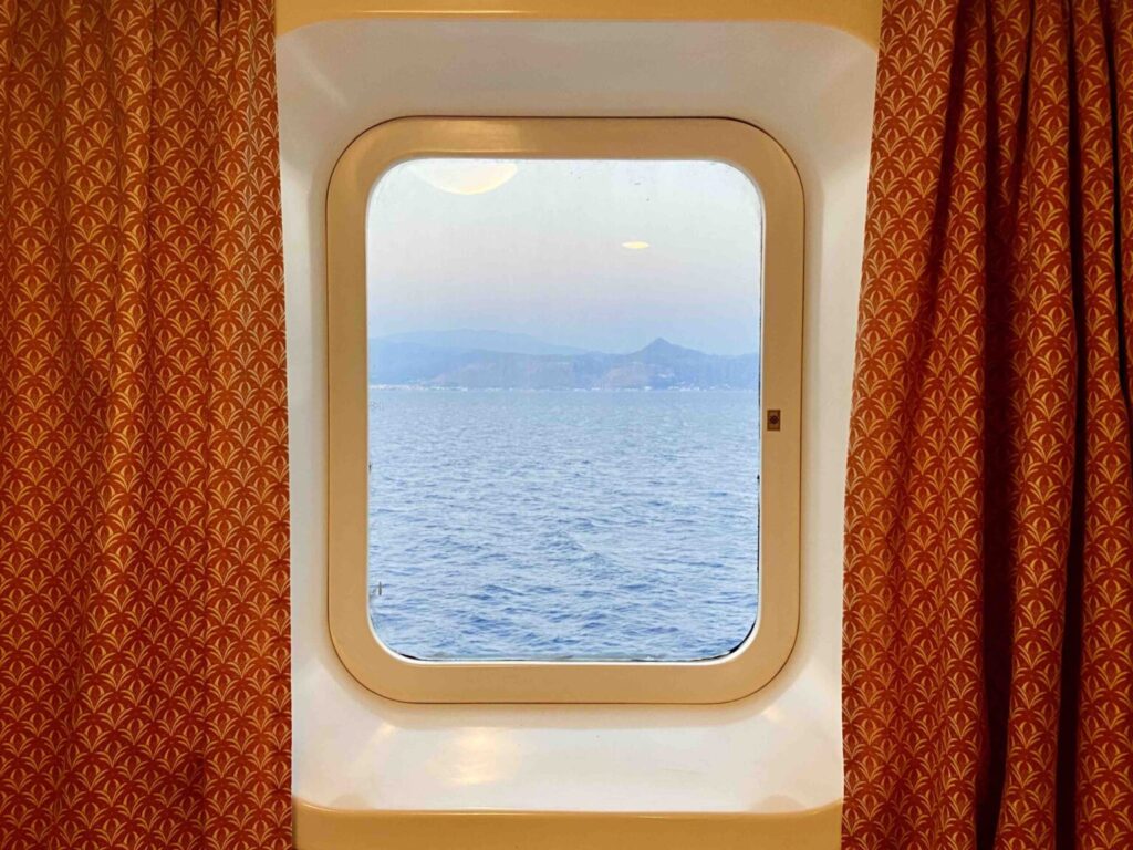 Orange curtains frame a window overlooking the blue ocean.