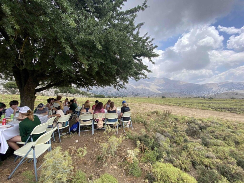 Students sitting in folding chairs with mountains in background.