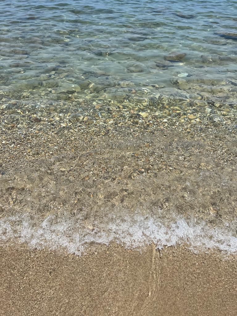 Crystal clear ocean water washing up on sand.