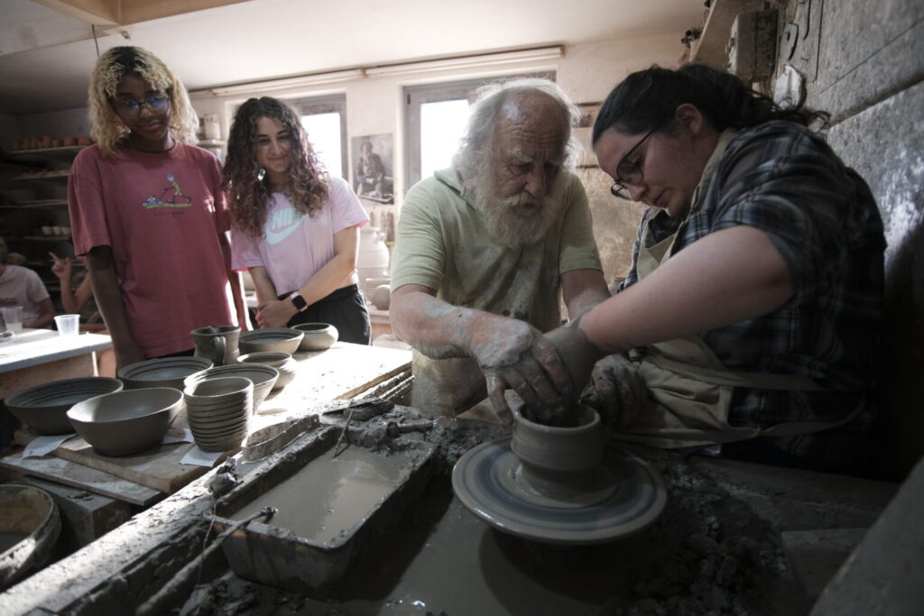 Man showing student how to make clay bowl.