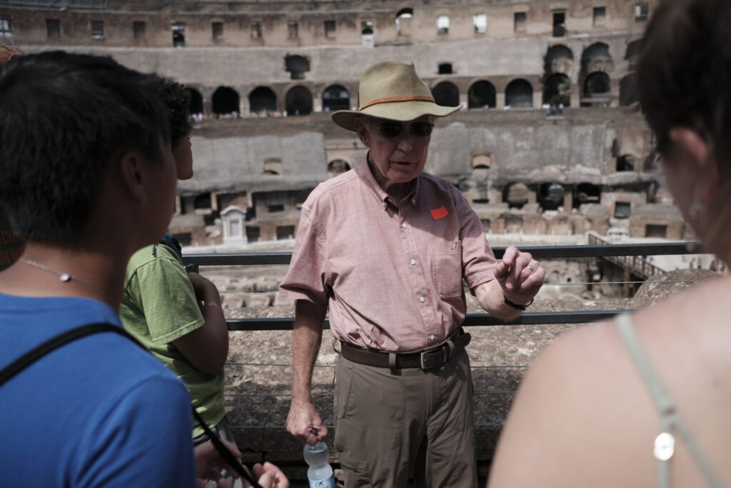 Guide speaking with students in front of old Colosseum.