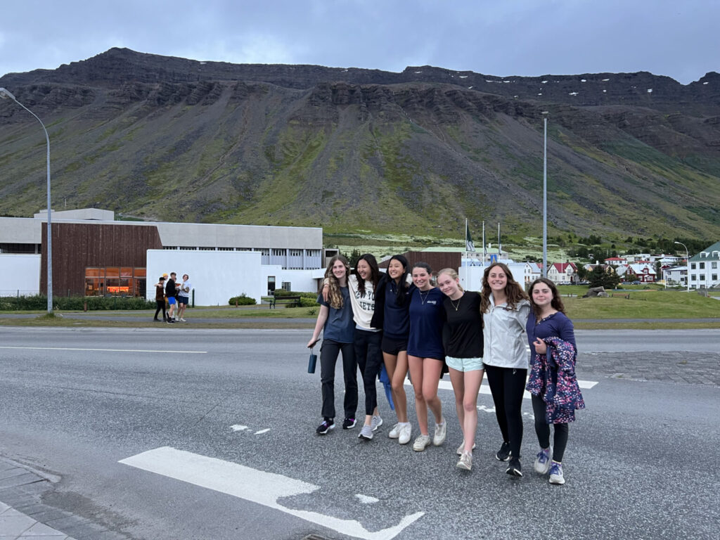 Students smiling while standing on pavement.