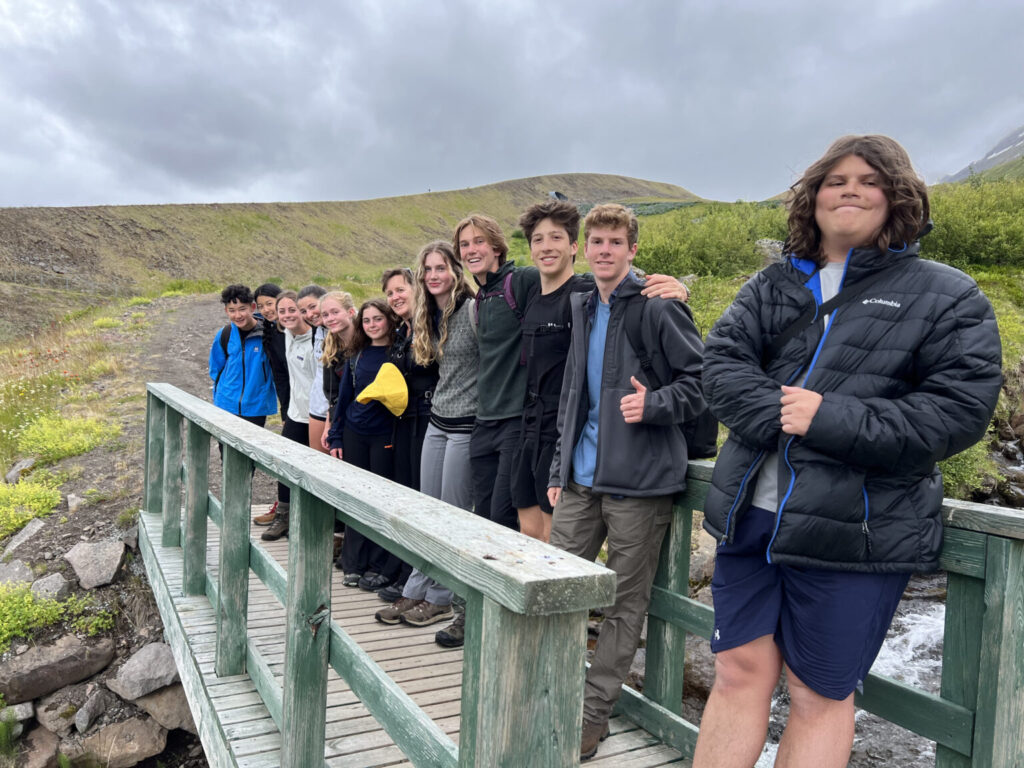 Group of students posing together on a green wooden bridge.