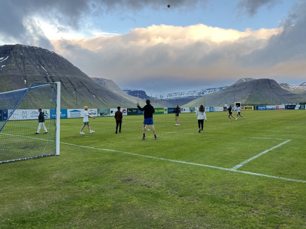 Students playing soccer on green field.