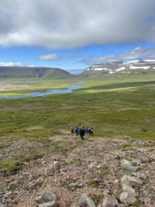 students hiking across green field