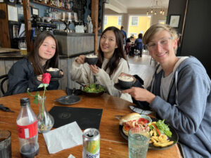 group of three students holding food up while eating lunch