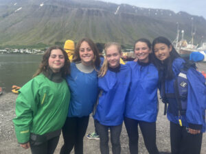 group of five girls smiling together in rain jackets