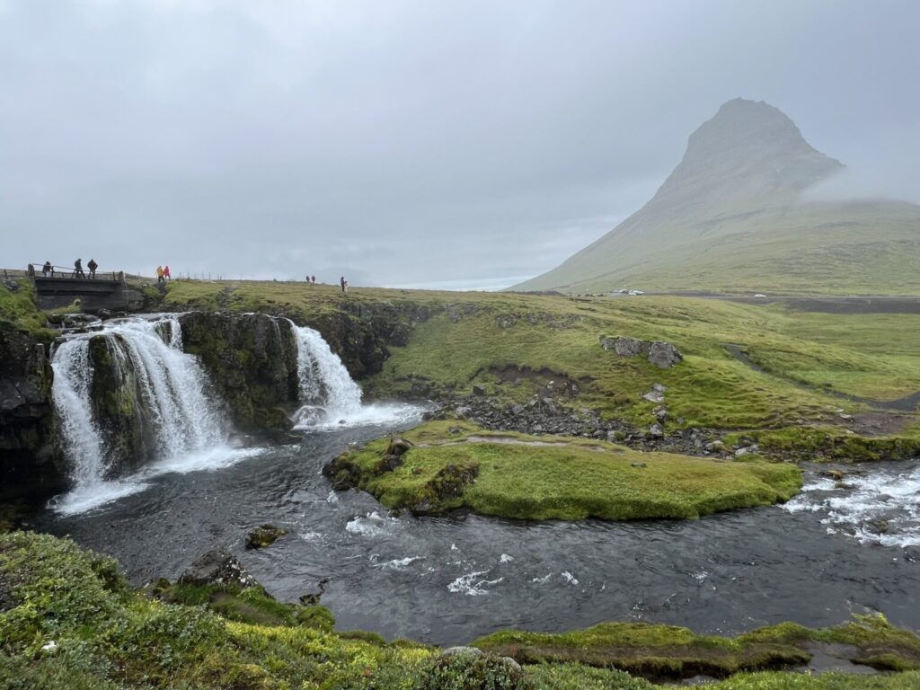 Waterfall in front of green grass.