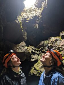 Two students looking up at cave opening.