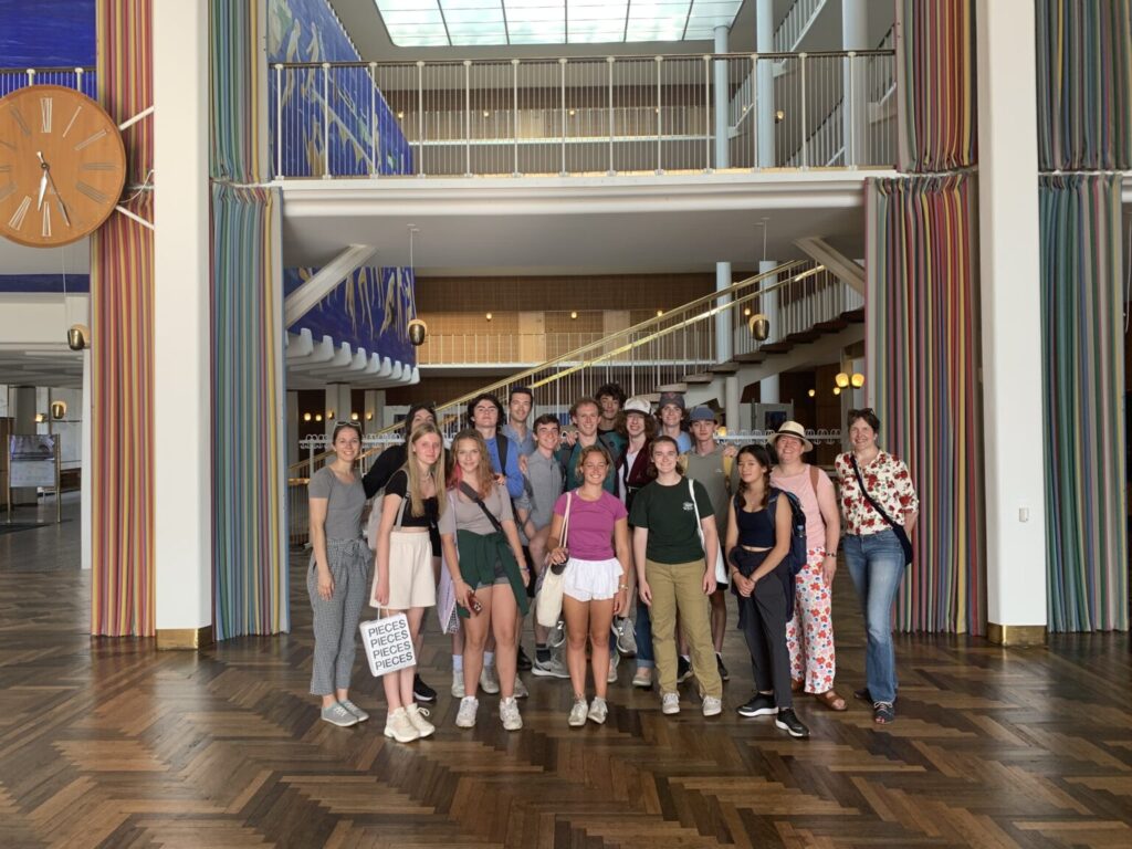 Group of students smiling in front of colorful staircase.