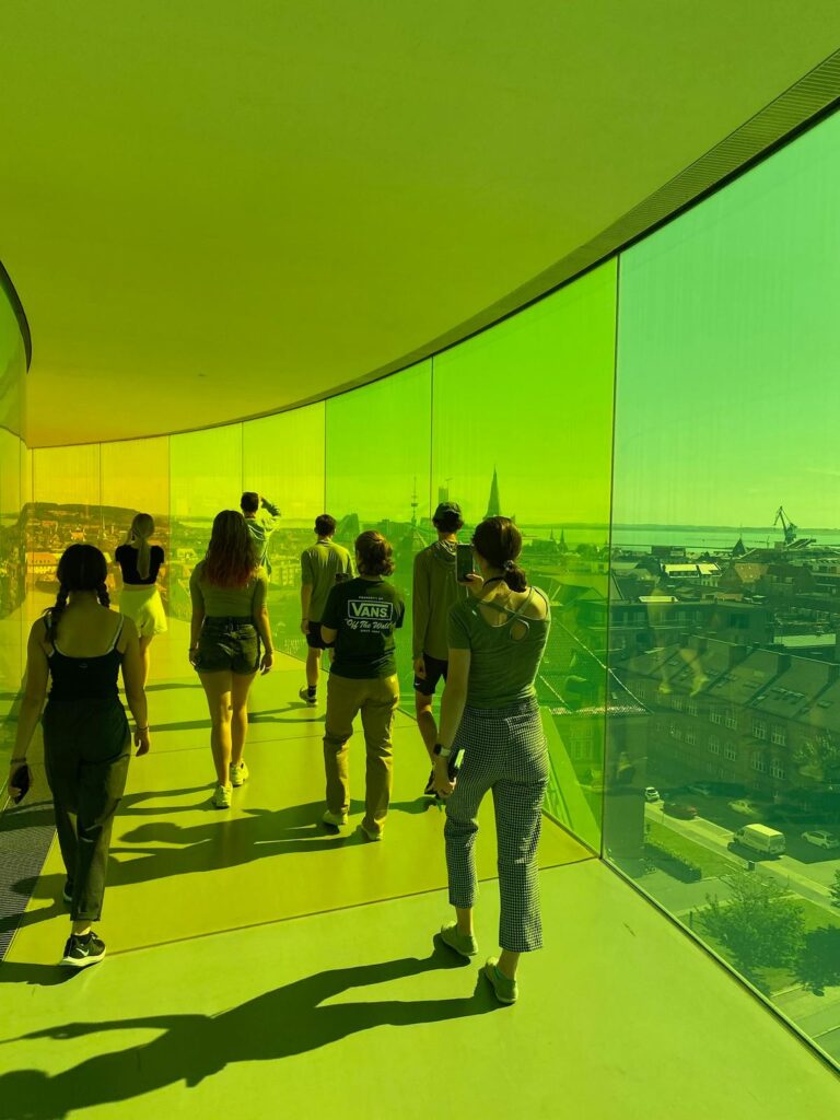 Students walking in glass tunnel lit up in green.