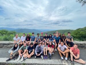 Group of student sitting in front of green fields.