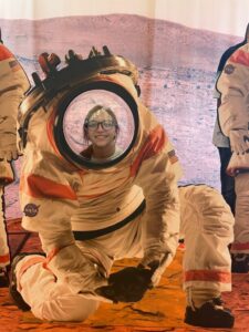 Student smiling posed in a space suit.