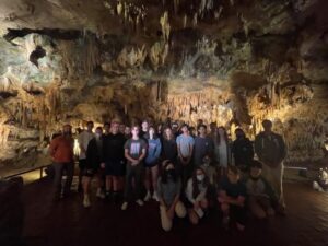 Group of students standing in dark cavern.