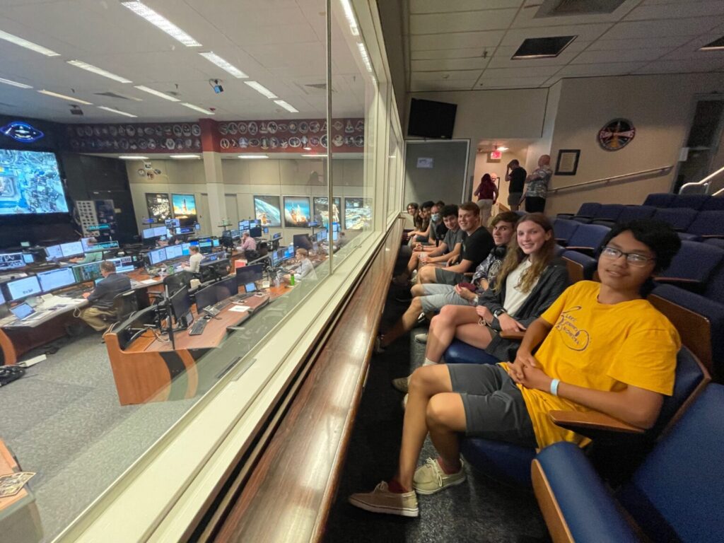 Students sitting in chairs behind plexi glass to watch mission control in action.