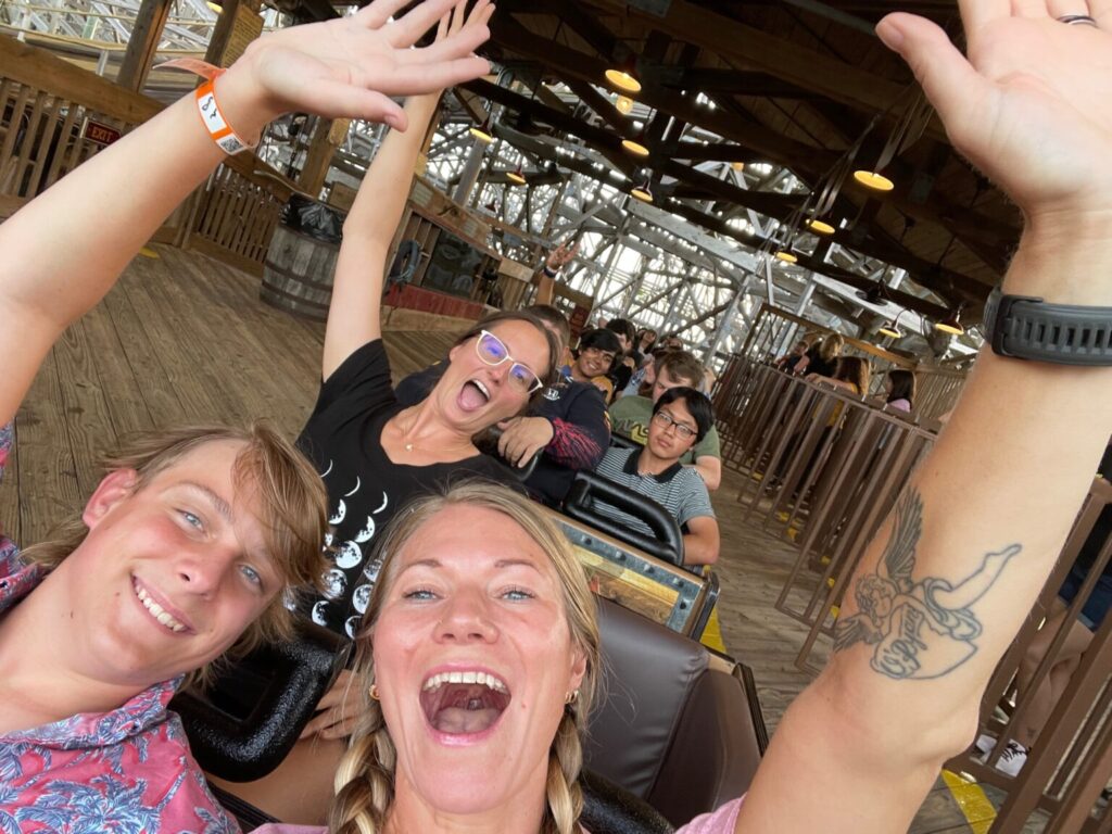 Students with arms up smiling on ride.