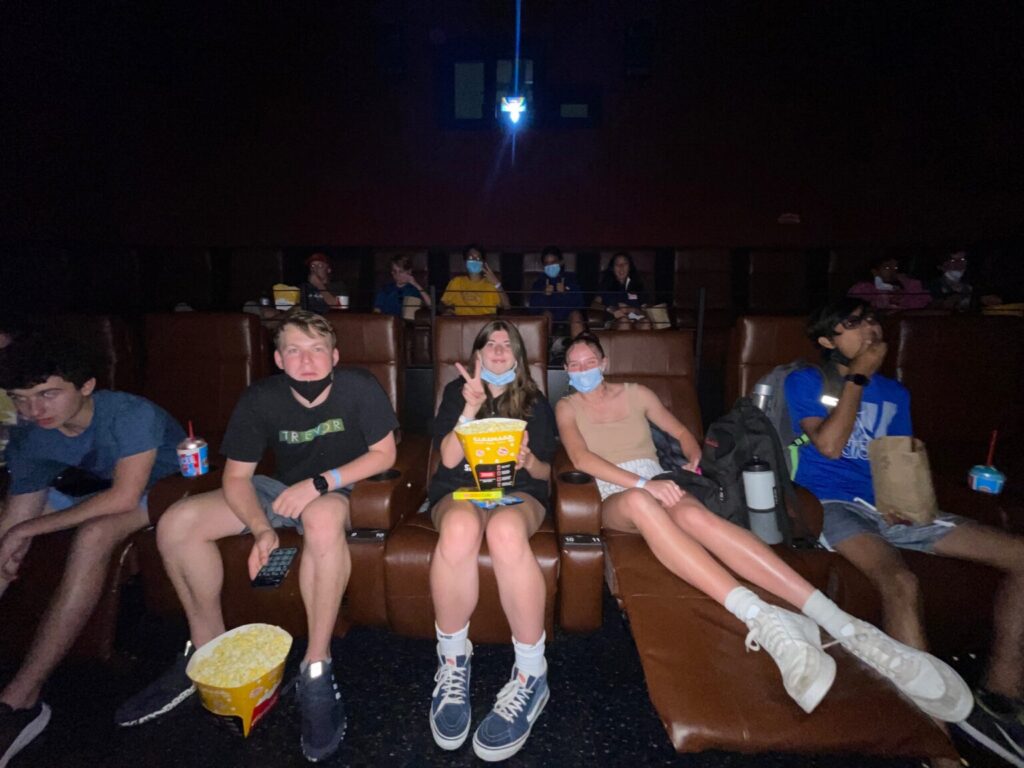 Students sitting in movie chairs holding popcorn.