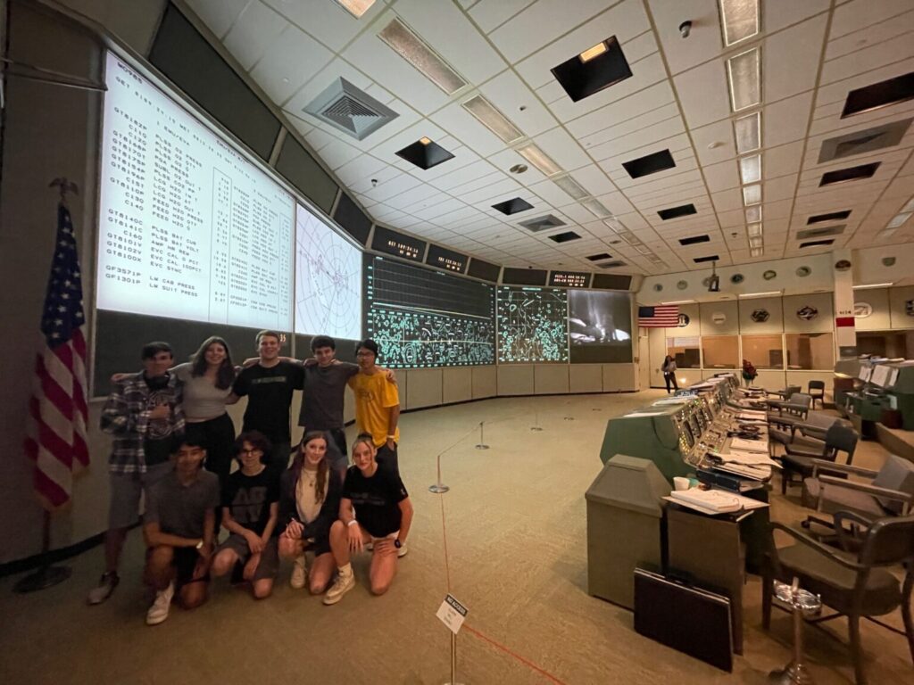 Group of students smiling standing in front of Apollo Mission Control Center.